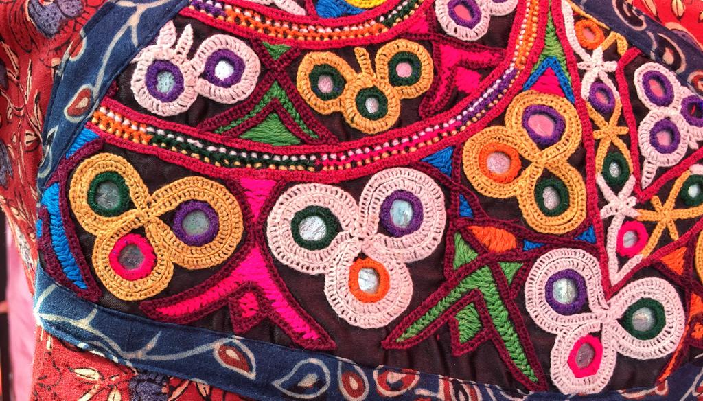 Mirror work embroidery with colorful threads and small mirrors on a black fabric